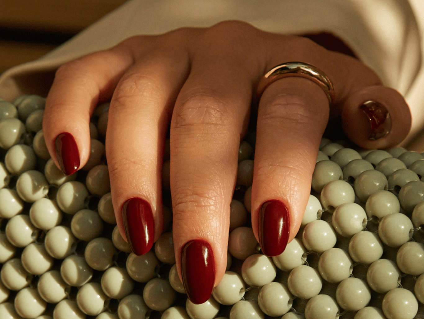 A close-up of manicured hands with deep red BIAB nails, showcasing the flawless finish after a professional BIAB infill treatment in Eastbourne.