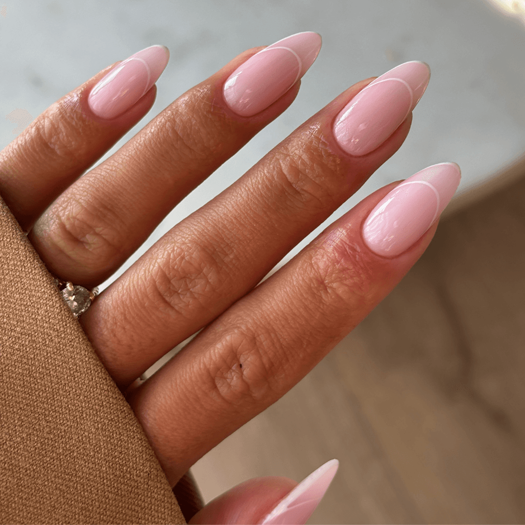 A close-up of perfectly shaped natural nails with a glossy nude-pink BIAB overlay, showcasing strength and elegance in a minimalist style.