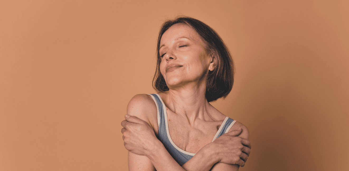 Confident middle-aged woman enjoying a moment of self-care, smiling with eyes closed against a warm background – perfect for promoting beauty and wellness at Dolls House Hair & Beauty Boutique in Eastbourne.