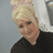 Donna, a professional beauty therapist and hair stylist at The Dolls House in Eastbourne, smiling warmly in front of a salon mirror and floral background.