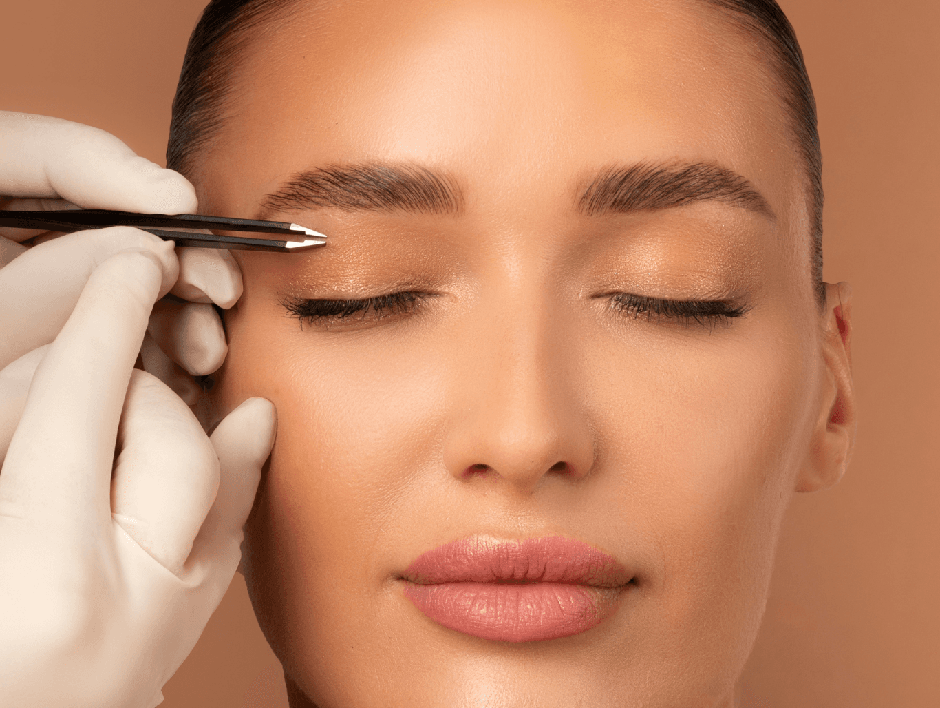 A beauty therapist carefully shaping a client’s eyebrows with tweezers during a precision eyebrow grooming treatment at a salon in Eastbourne.