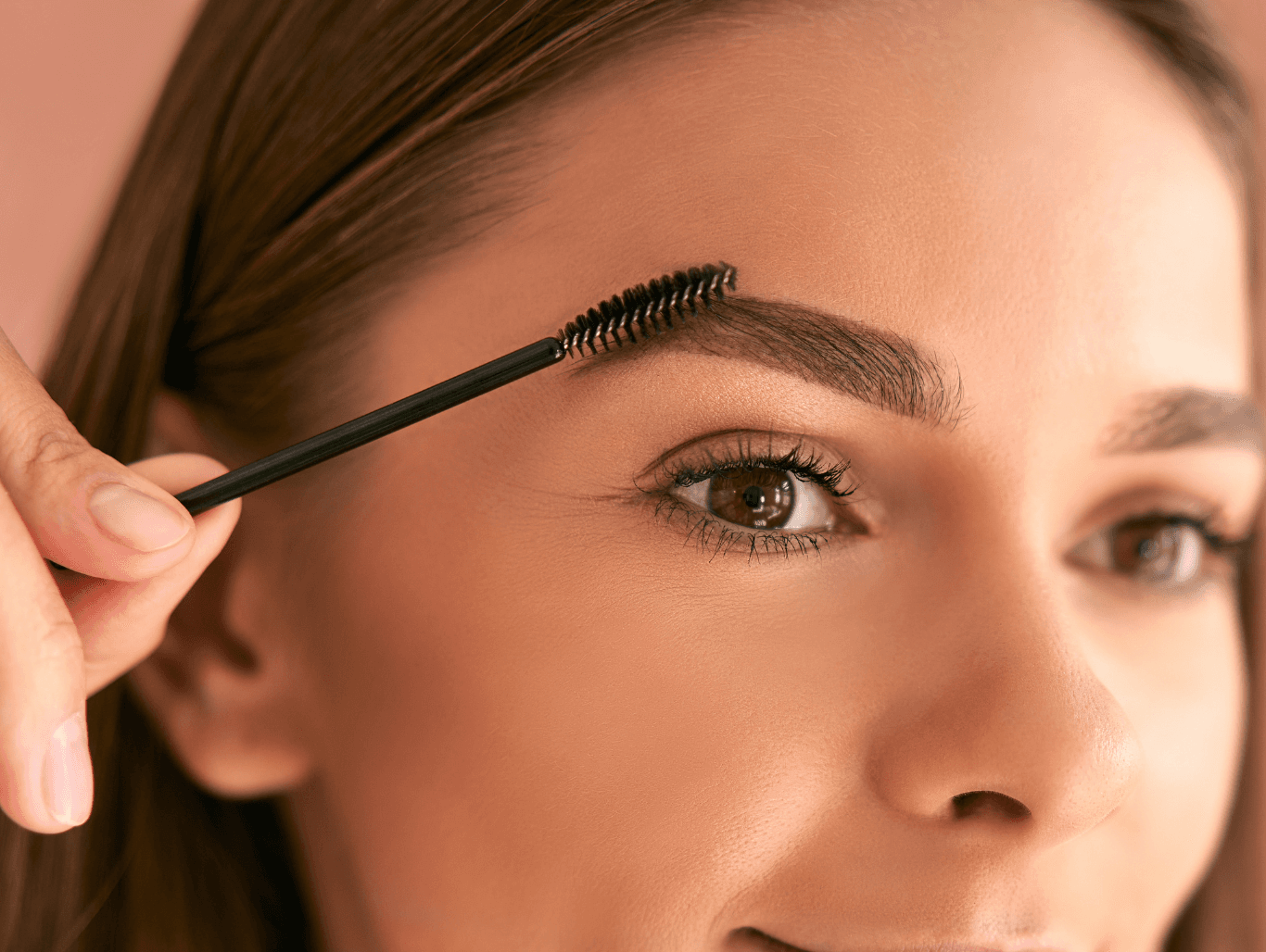 A beauty therapist brushing through freshly tinted and shaped eyebrows on a smiling client during a brow wax and tint treatment in Eastbourne.