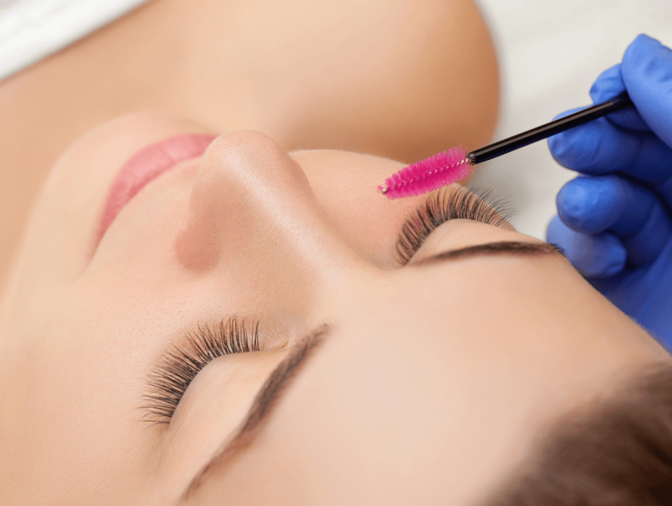 A beauty therapist brushing through freshly tinted lashes on a relaxed client during an eyelash and eyebrow tinting treatment in Eastbourne.