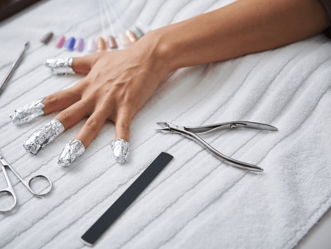 A close-up of a client’s hand with foil wraps on each finger, showing the professional gel polish removal process at a nail salon in Eastbourne.