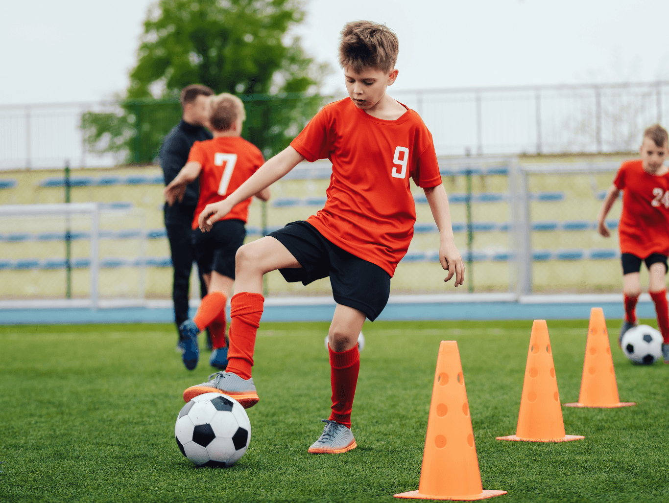 Young boy in football training session, dribbling through cones during a coaching session in East Sussex.