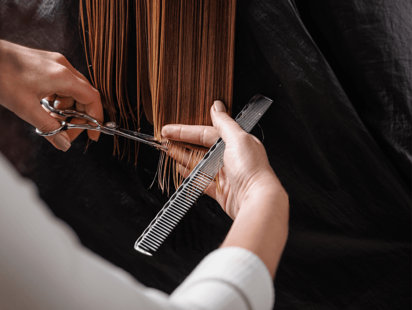 A stylist cutting freshly washed, straight hair with precision scissors and comb, during a ladies’ wash and cut service at The Dolls House in Eastbourne.