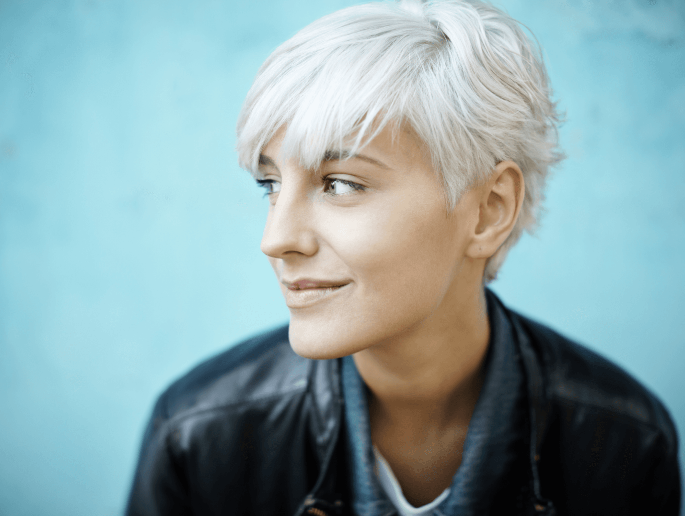 A confident woman with icy blonde hair styled in a soft pixie cut, showcasing the results of a root bleach and tone service at The Dolls House salon in Eastbourne.