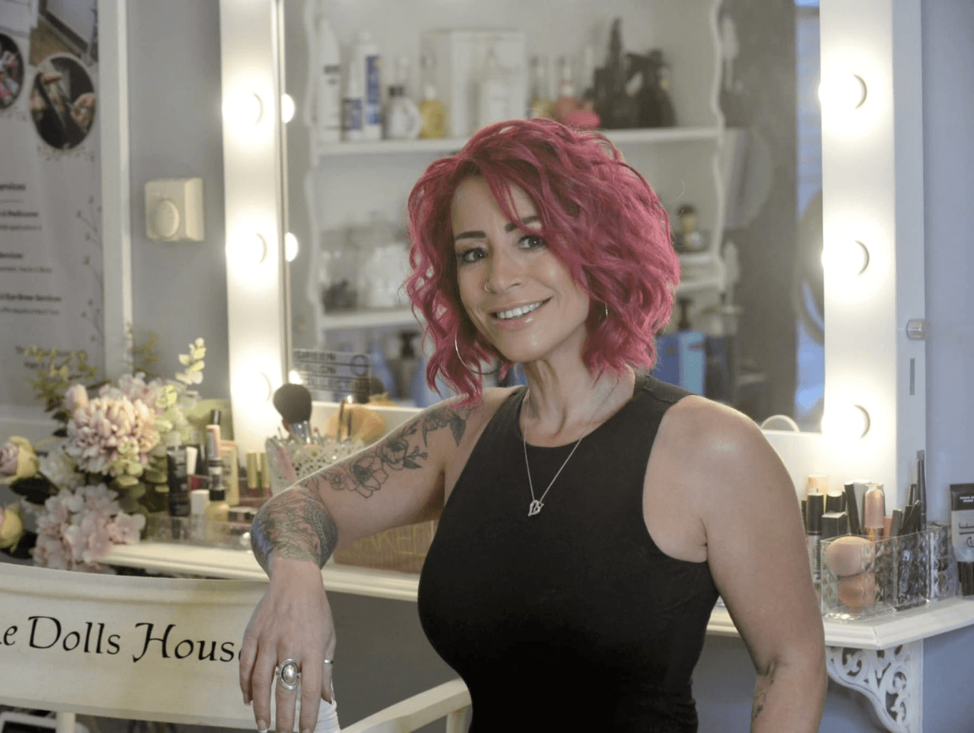 Belle, owner of The Dolls House Hair & Beauty Boutique in Eastbourne, smiling in the salon’s makeup and styling area – expert in inclusive hair and beauty services.